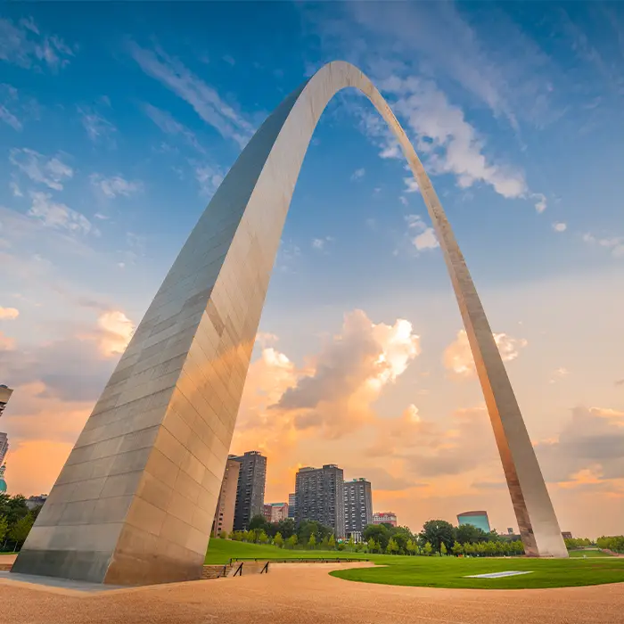 A view of the Gateway Arch from ground level. The St. Louis city skyline is visible behind the Arch.